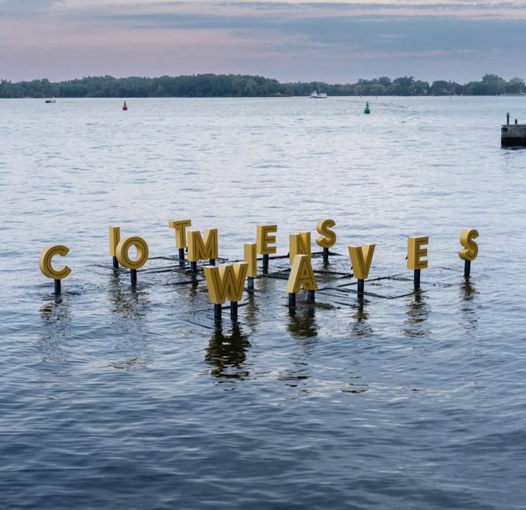 It Comes in Waves — yellow floating letters on the lake at Little Lake Park, Midland
